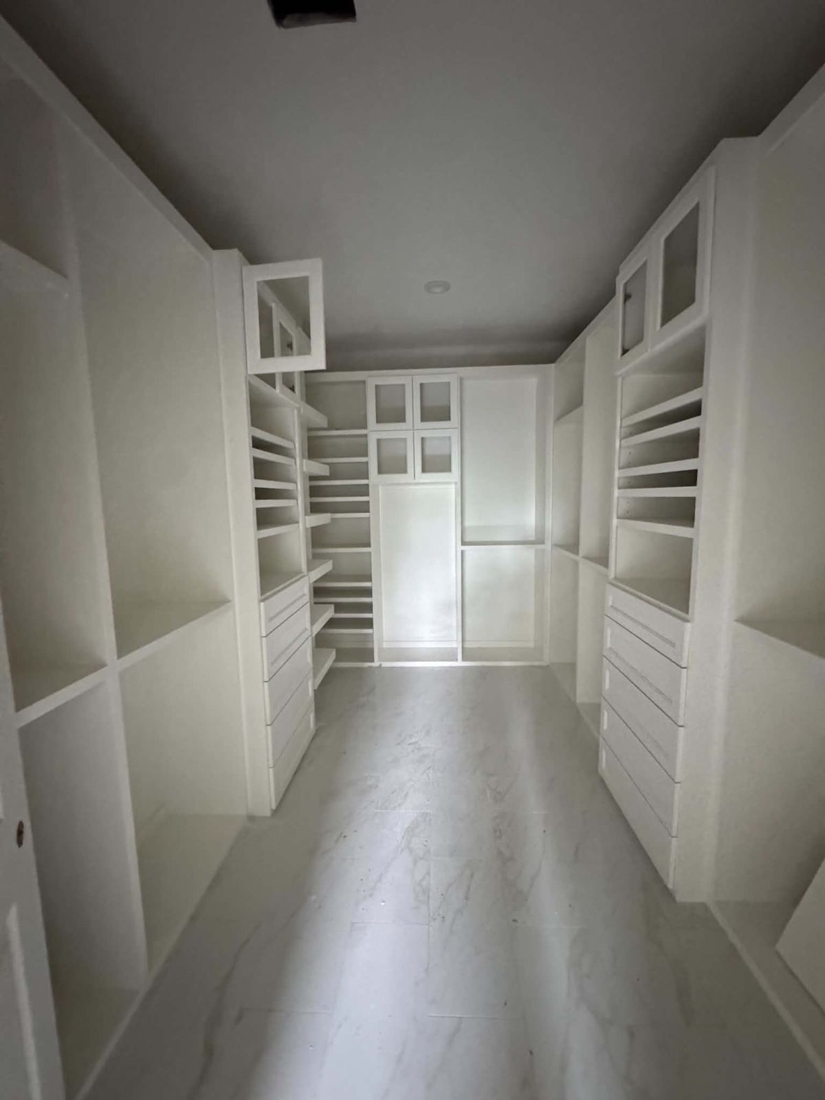 White custom walk-in closet with drawers, shelves and glass-front doors