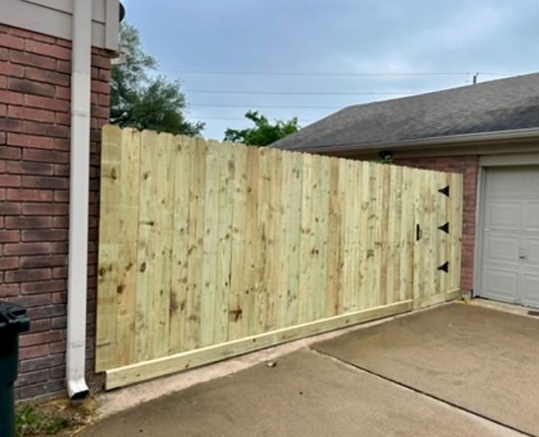 Wood fence and drive gate beside a brick home